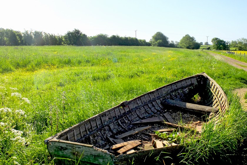 old wooden rowing boat in a field
