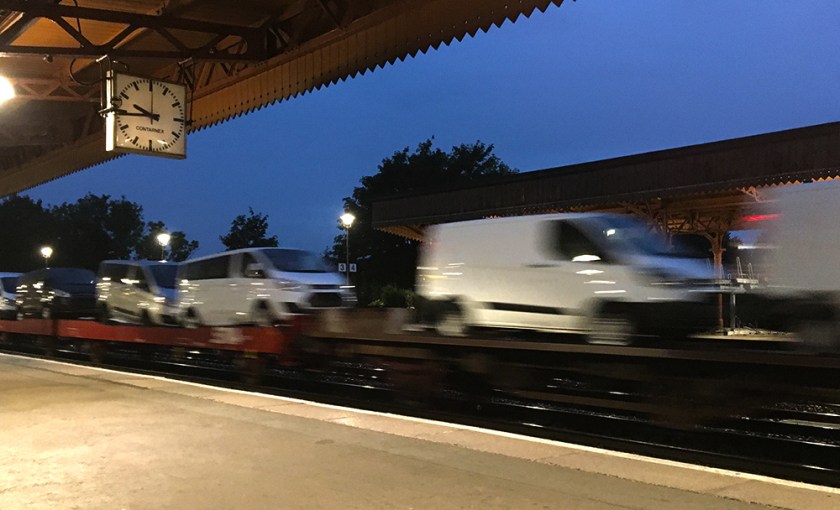 White vans being transported by rail