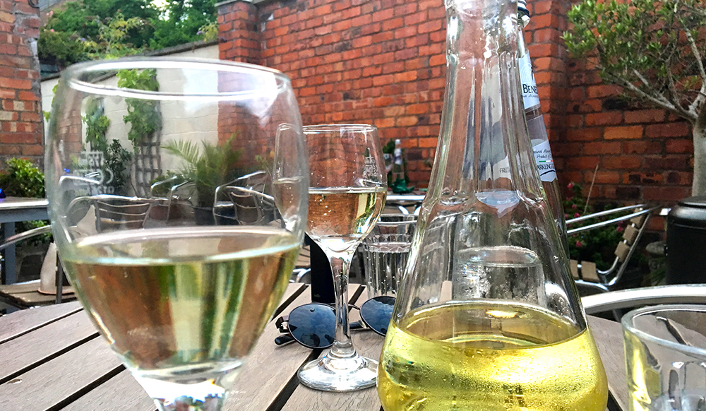 white wine carafe and half-full glasses on wooden outdoor table