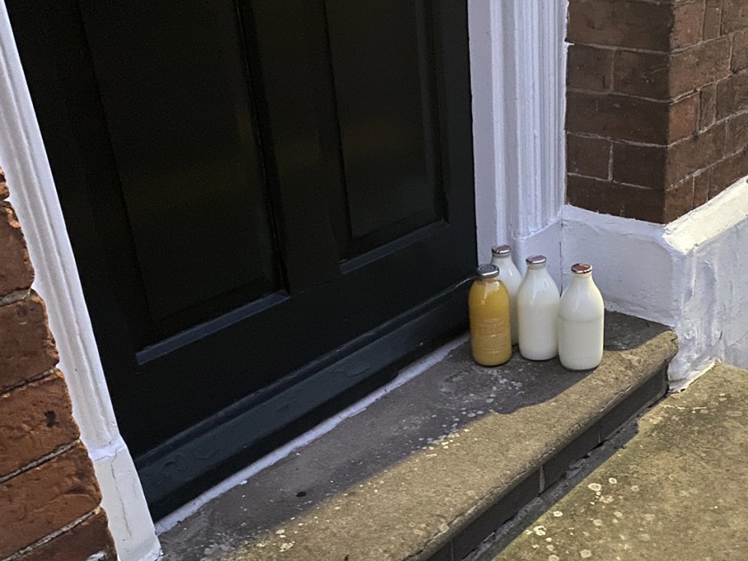 milk and orange juice in bottles on a doorstep